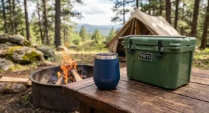 Double-wall vacuum insulated stemless wine tumbler sitting on a campfire ring table next to a portable cooler